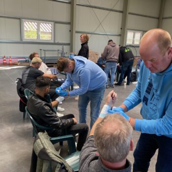 Beim Erste Hilfe Kurs üben die Mitarbeiter gegenseiteig sich einen Verband um den Arm zu wickeln