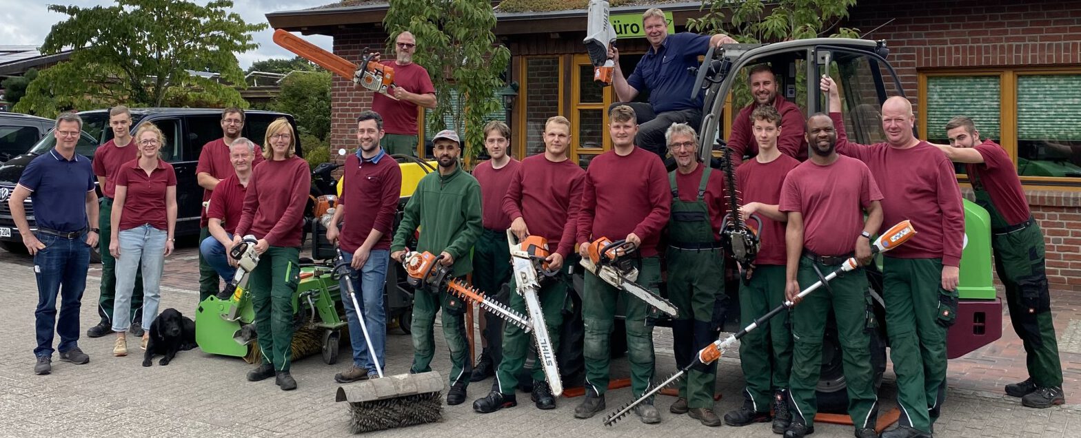 Gruppenfoto mit Motorsägen, Heckenschere und Betriebshund