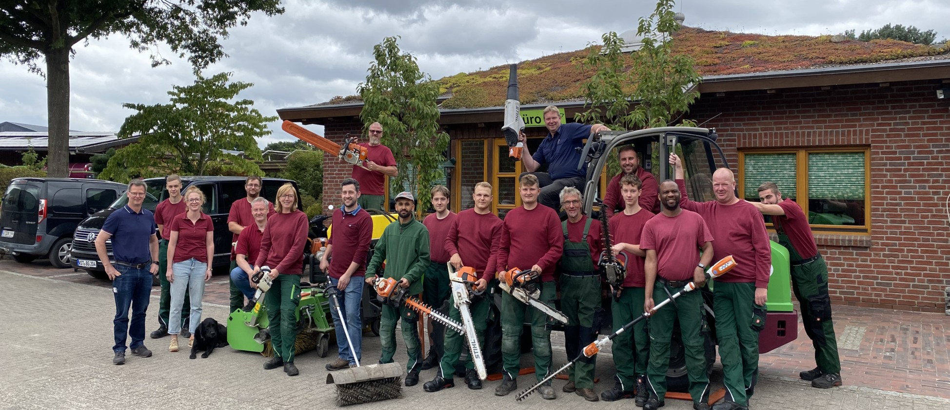 Gruppenfoto mit Motorsägen, Heckenschere und Betriebshund